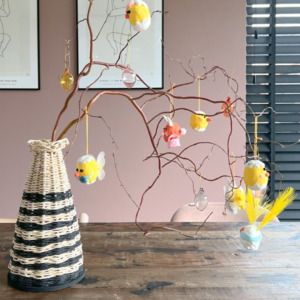 Mand met papier garen en maiskoord in een streep patroon met Paastakken en Paasdecoratie.