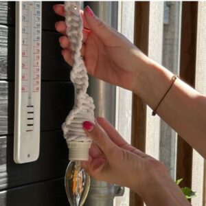 Laten zien van het macrame koord met de lamp in de tuin, hangend naast een tuin thermometer.