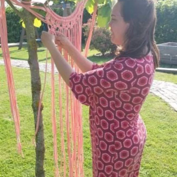 Vrolijk Haakmeisje knoopt haar macramé project met behulp van de waslijn, super slim!