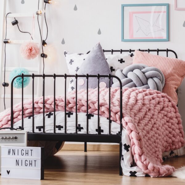 Roze deken van 5 kilo over een bed in een kinderkamer.