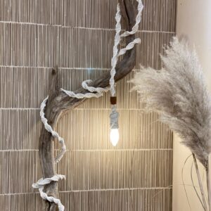 Lamp koord geknoopt met wit bobbiny garen in een bohemian stijl gefotografeerd met pluimen, een tak en riet behang.