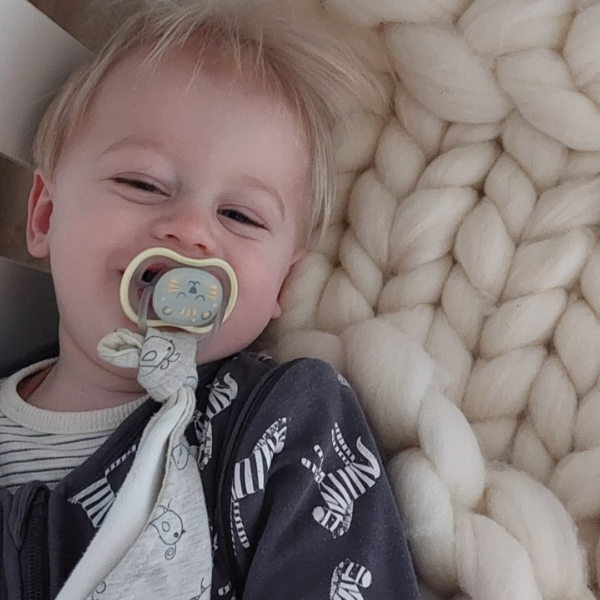 Baby bowie op een gebreide deken van lontwol om lekker op te slapen.