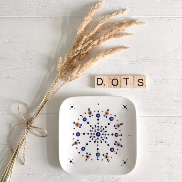 Dot painten en stippen op servies, een vierkant bordje beschilderd, met een pluim en scrabble letters DOTS erbij.