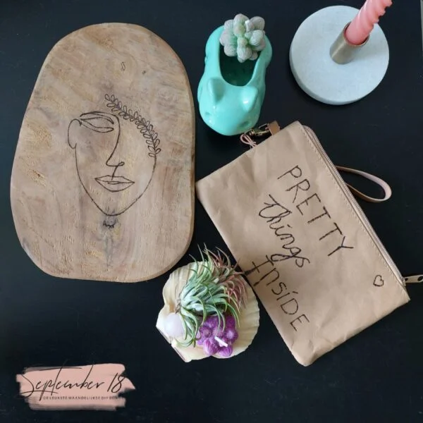 Tasje van nep leer gegraveerd door middel van hout branden, met een houten plank, bloemetjes en een kaars.