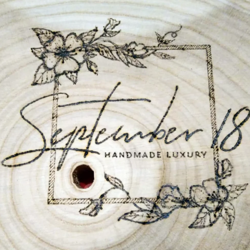 Het logo van September18 met houtbranden op een houten boomstam gedecoreerd.