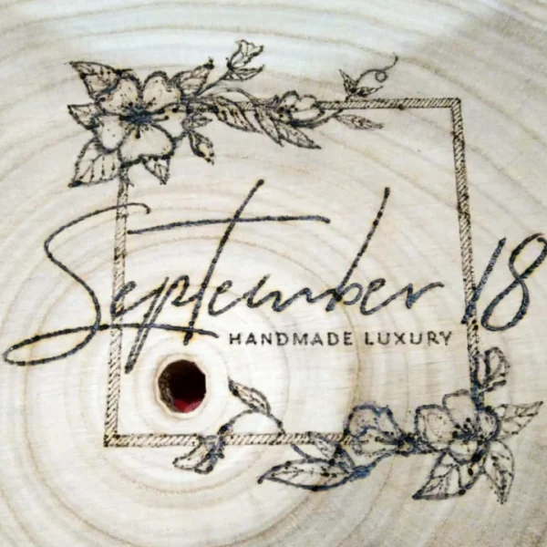 Het logo van September18 met houtbranden op een houten boomstam gedecoreerd.