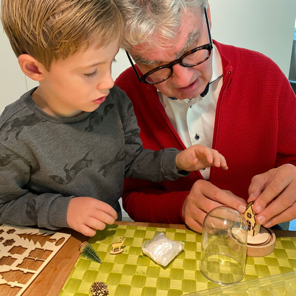 Een jongetje knutselt samen met zijn opa de kerst DIY van september18.nl aan de keukentafel.