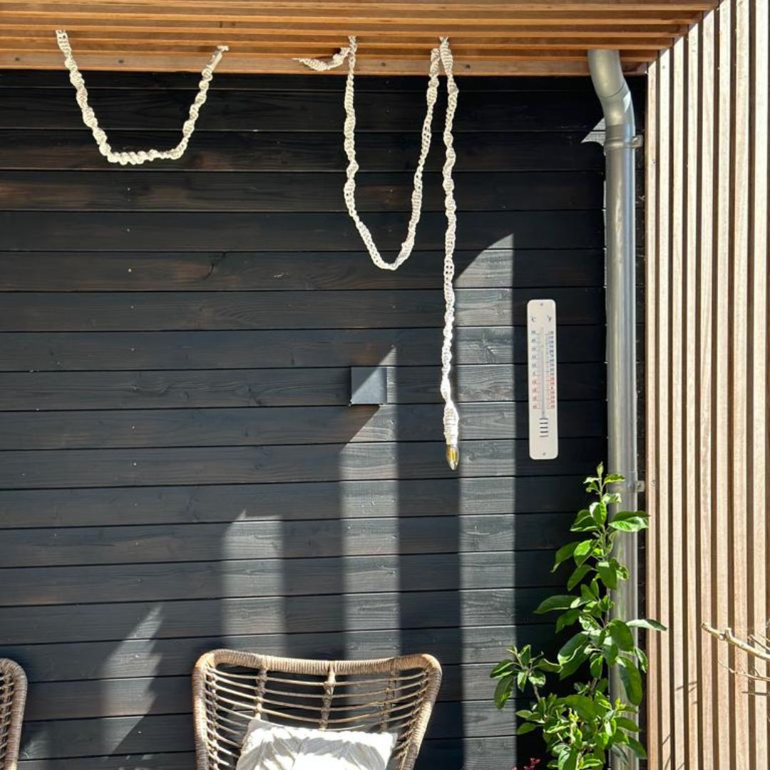Macrame lampkoord opgehangen buiten in de veranda met een stoel en plant.