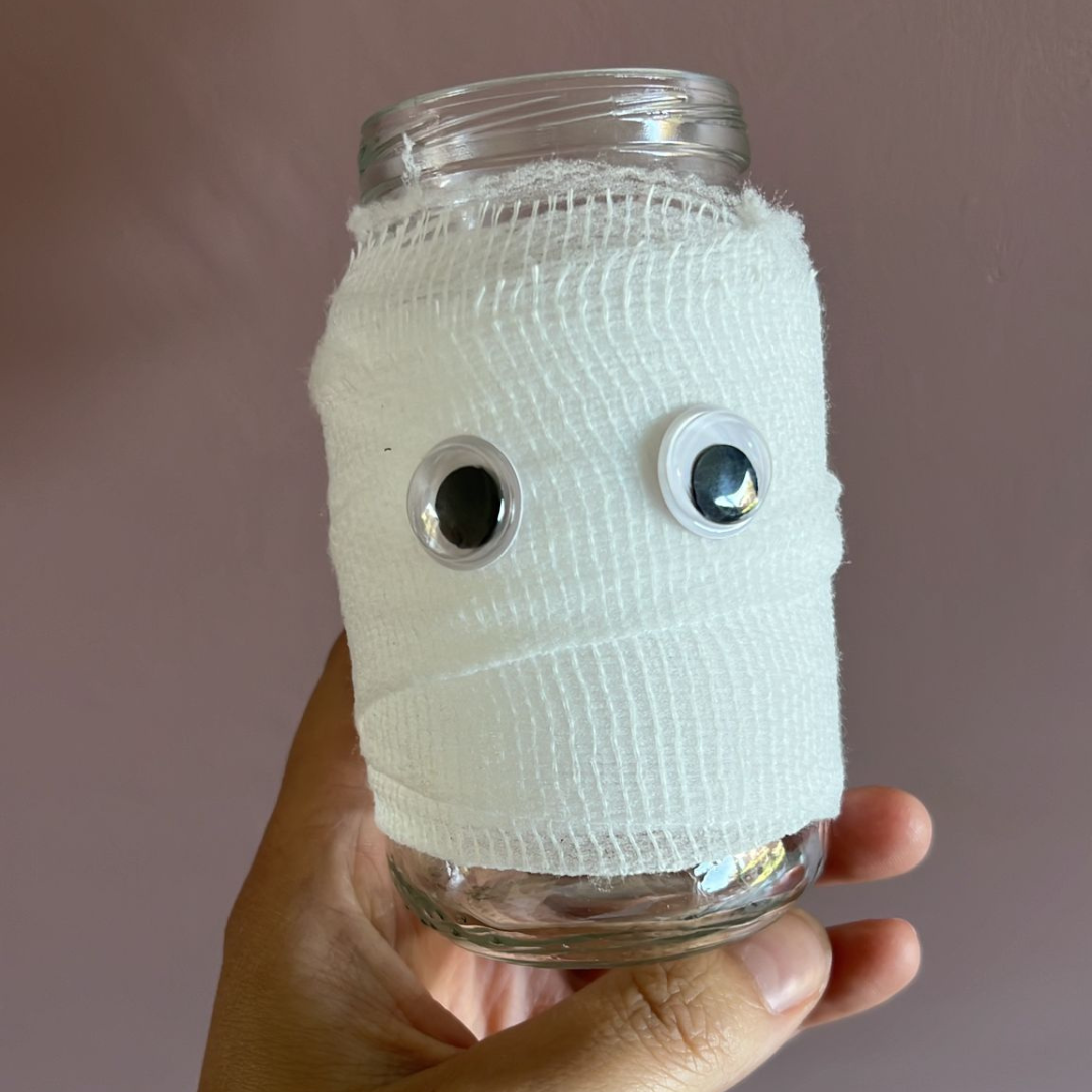 Halloween idee een glazen potje met wit rekverband erom en oogjes erop om een spookje te maken.