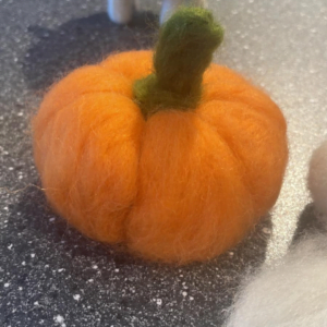 Oranje pompoentje van lontwol geprikvilt.