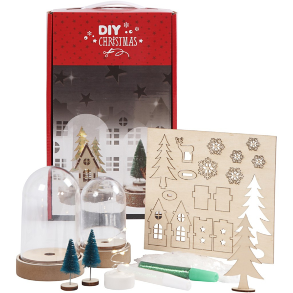Een doos met de inhoud van het DIY kids kerstpakket uitgestald op tafel met stolpjes, houten accessoires en een glitterpen.