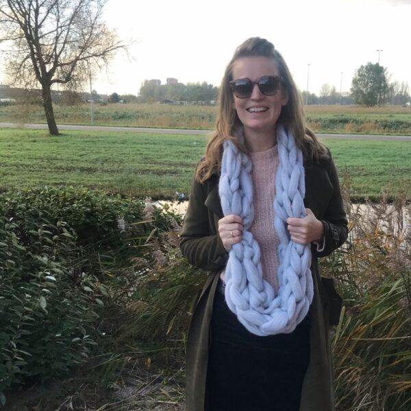 Sarah buiten met een warme sjaal van lontwol om haar nek in een groen park.