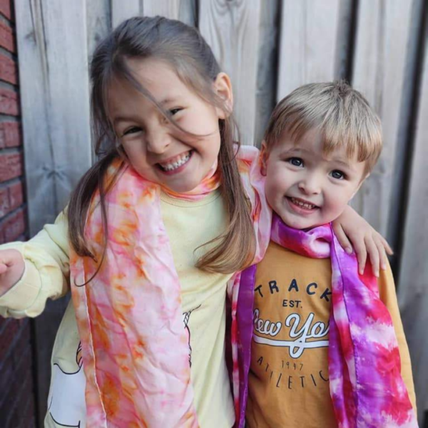 Jill en Morris samen met hun tie dye zijden sjaal om hun nek in felle en zachte roze, paars en oranje tinten.