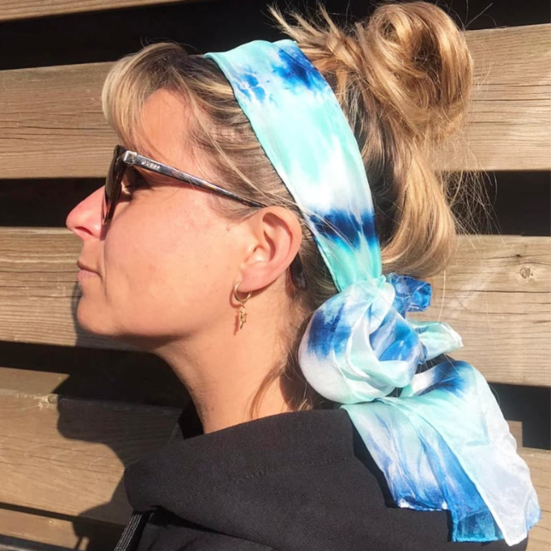 Een sjaal van zijde geschilderd met de Tie Dye techniek in haren gebonden ter bescherming tegen zonlicht.