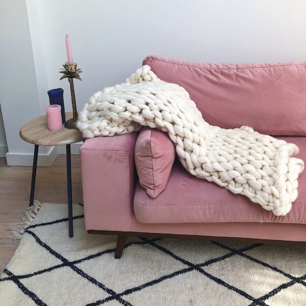 Voorbeeld van een deken over een roze bank in de woonkamer gemaakt met het patroon deken breien met lontwol.