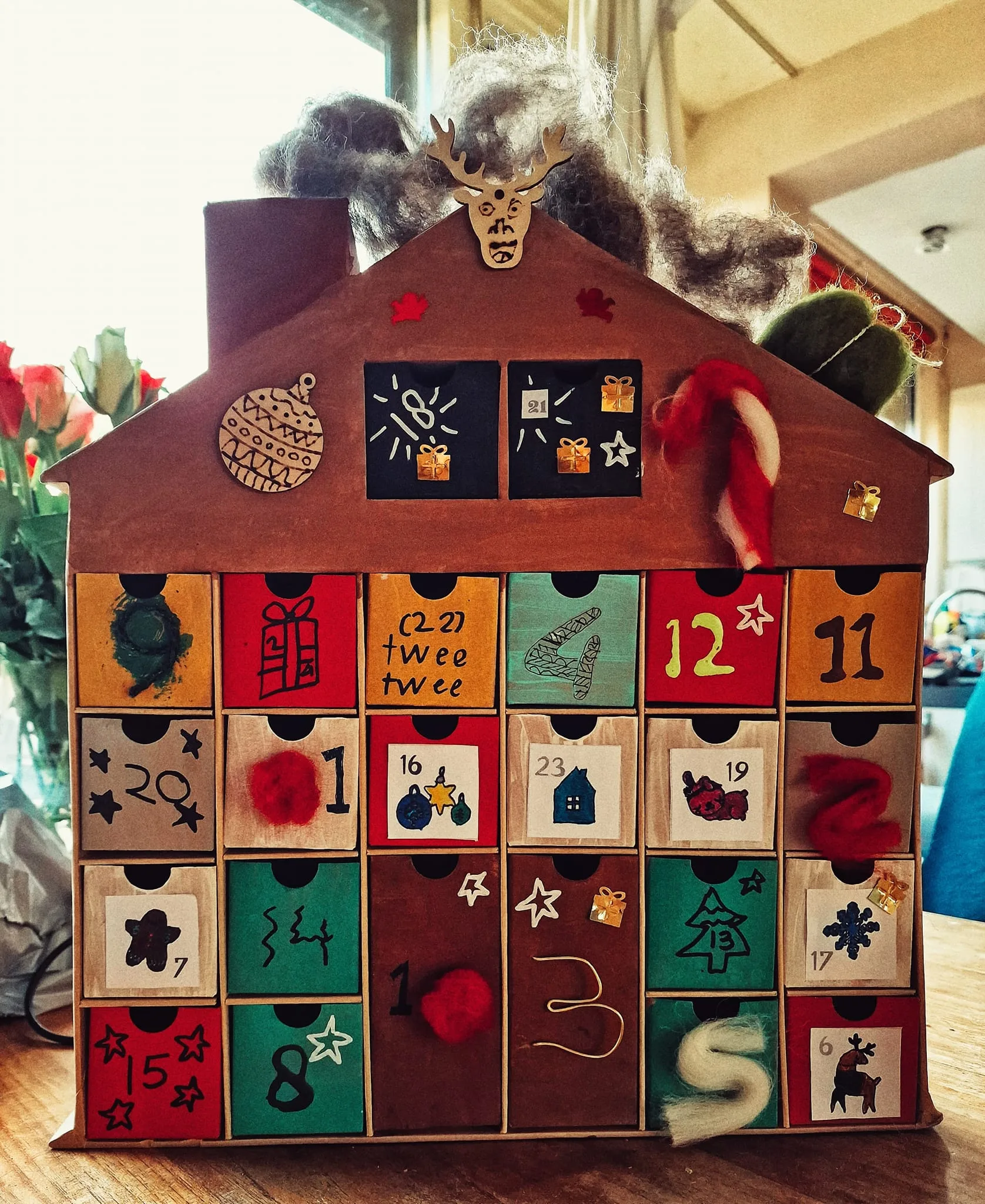 Voorbeeld DIY adventhuis geknutseld met papier, stickers, verf en kerstversiering.