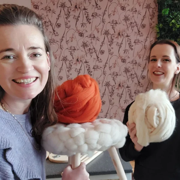 De nieuwe box van december is een melkkruk van huis met een gebreide hoes van wol, en Sarah en Sarina houden allebei een bol wol vast.