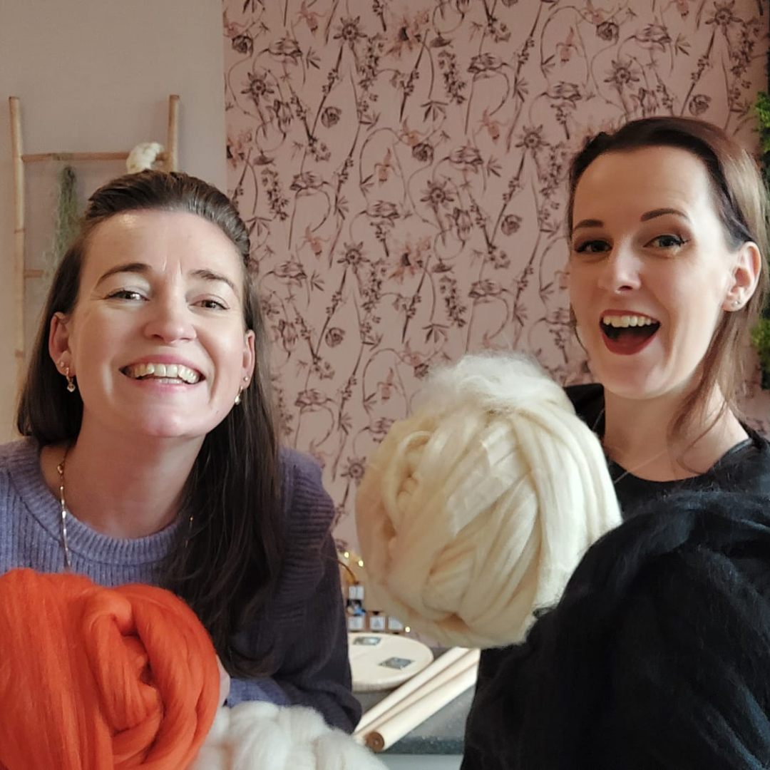 Sarah links met een oranje bol wol en Sarina rechts met een ivoorkleurige bol wol.