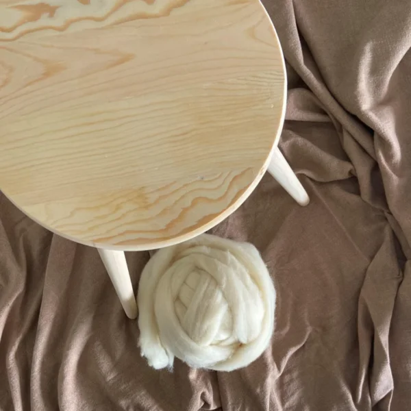Houten kruk met houten poten naast een bol met lontwol in Ivoor.