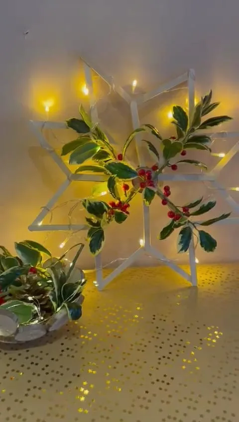 Leuke makkelijke kerst DIY van ijsstokjes versierd met lampjes en hulst.