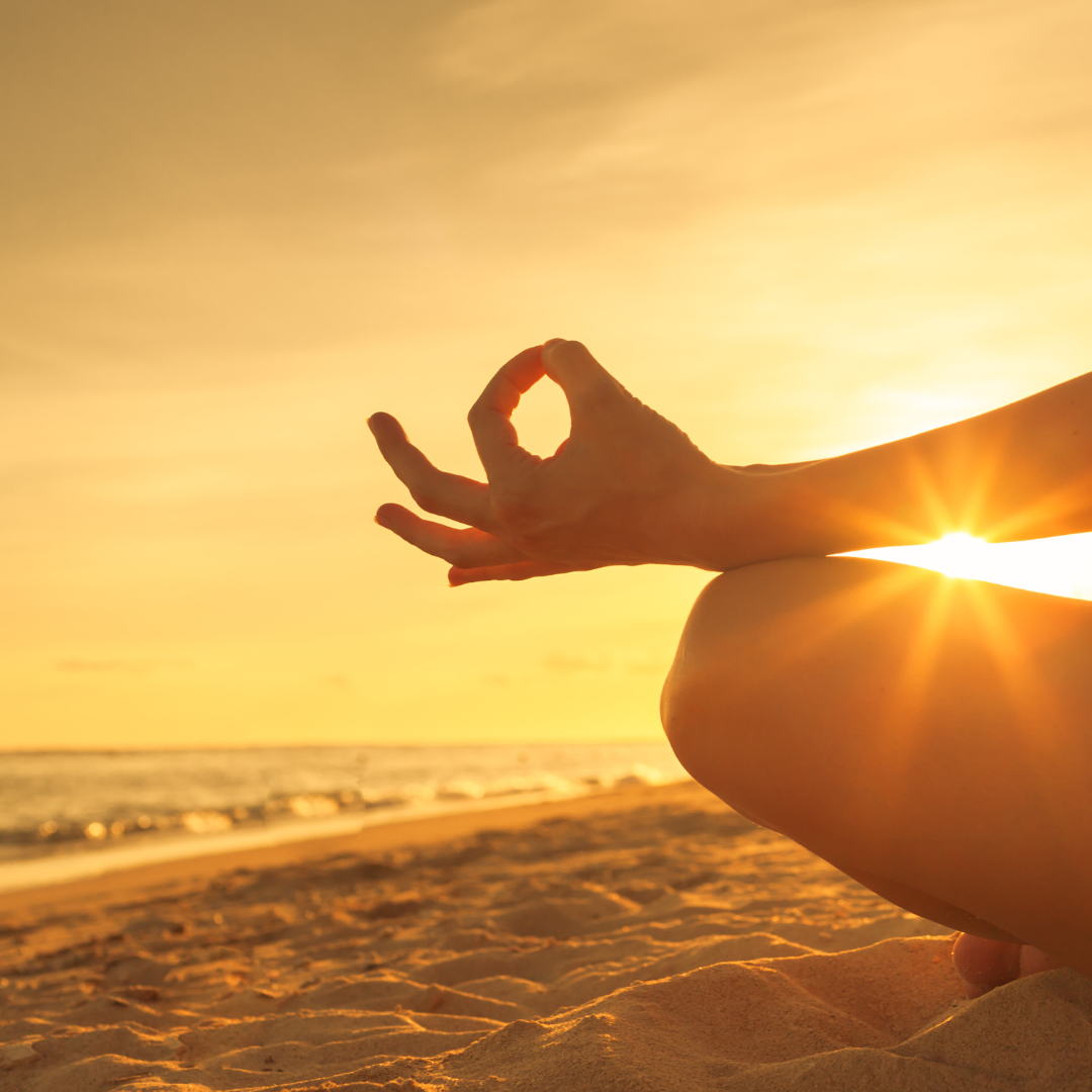 Foto van een meditatie op het strand om tot rust te komen bij de ondergaande zon.