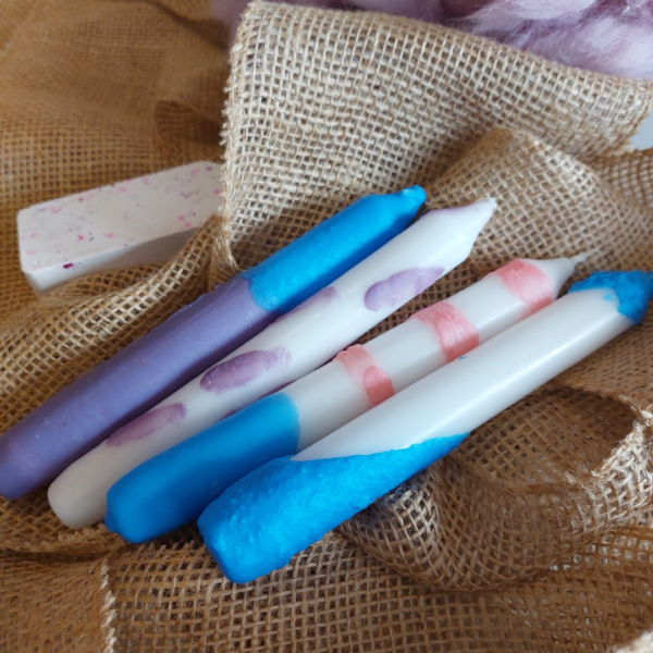 Voorbeeld van geverfde kaarsen in blauw en paars op een jute zak ter decoratie.