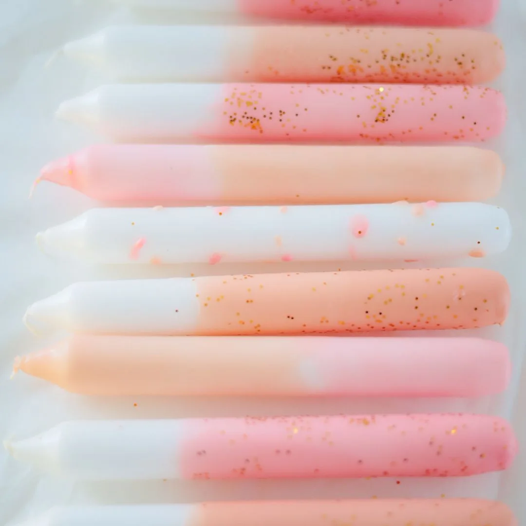 Dip Dye kaarsen in verschillende pastel tinten, van zacht roze tot abrikoos.