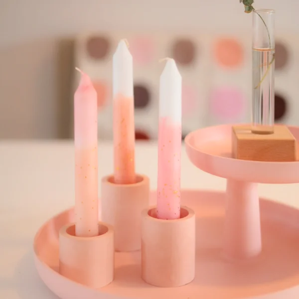 Prachtige kaarsen geverfd in pasteltinten in eigen gemaakte kaarsenhouders in roze op een dienblad.