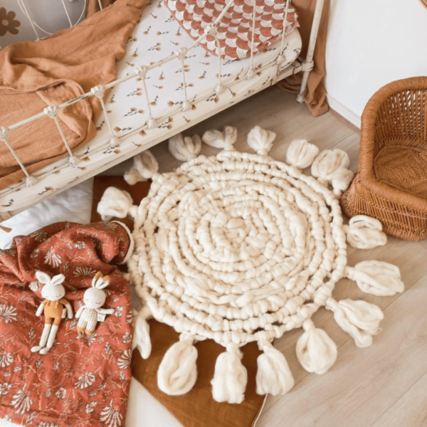 Rond vloerkleed van ivoorkleurige lontwol geknoopt met de Macrame techniek in de kinderkamer.