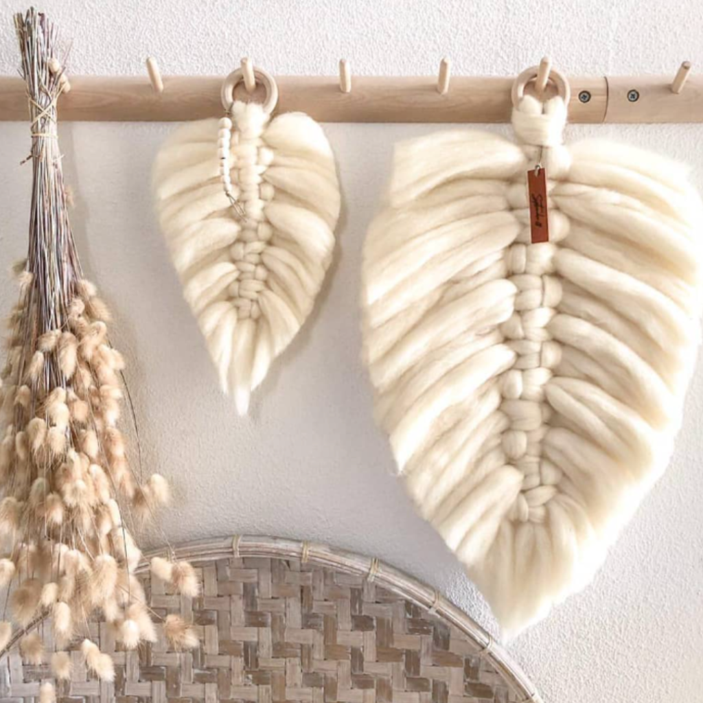 Veren van lontwol in ivoor in groot en klein formaat hangend aan een houten kapstok met decoraties in Scandinavian style.