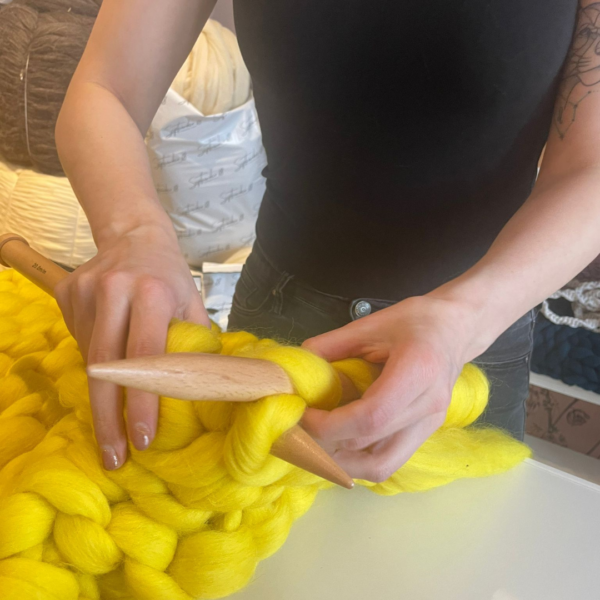 Kussen breien met gele lontwol op XXL houten pennen.