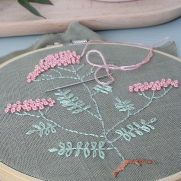 Wandhanger geborduurd met bloemen en bladeren in zachtgroen en roze.