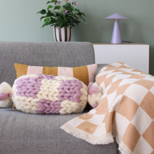 Gebreid lontwol blush Ivory blush in een woonkamer, gestyled op de bank.