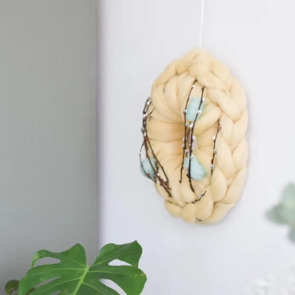 Paaskrans met zachtgele lontwol en Paas decoratie aan de wand.