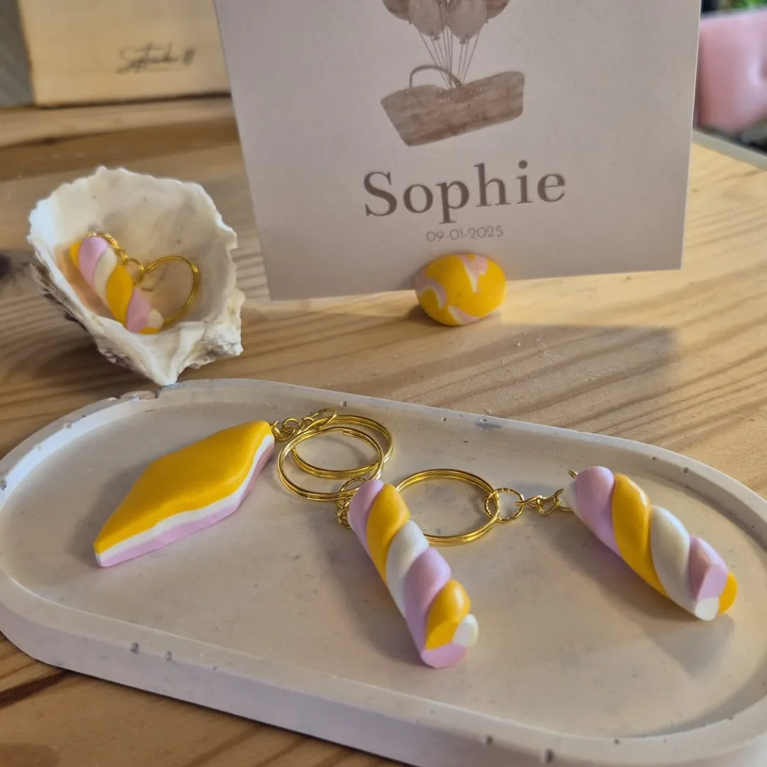 Schaaltje met daarop twee verschillende spekjes sleutelhangers en een oester schelp met sleutelhanger.