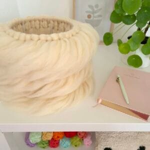 Lontwol lamp op tafel met plant en boekje.