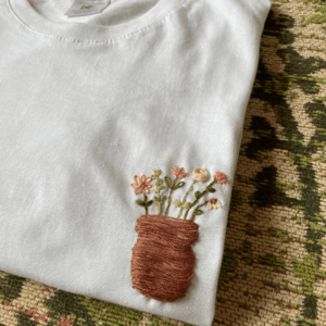 Detail Jeanet met wit t-shirt met daarop het borstzakje met bloemen geborduurd.