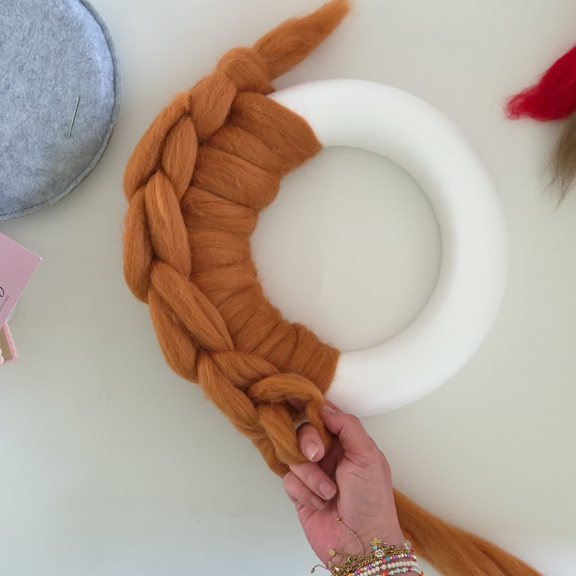 Knoop de lontwol om de krans heen met een macrame techniek.